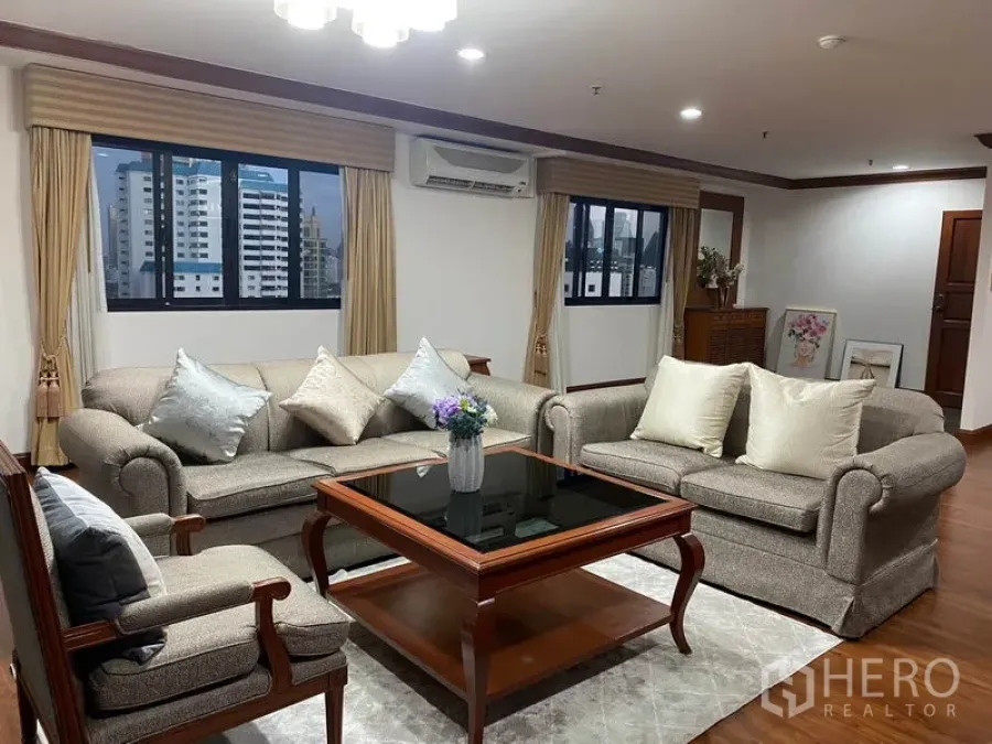 Condominium for rent in Watthana, Bangkok - Spacious living room with grey sofas, glass coffee table, city-view windows and wooden floors.