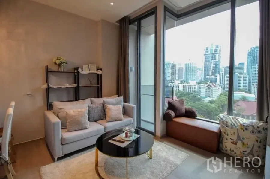 公寓 出售在Watthana, Bangkok - 客厅带窗边座与落地玻璃通往阳台，框景城市风光。