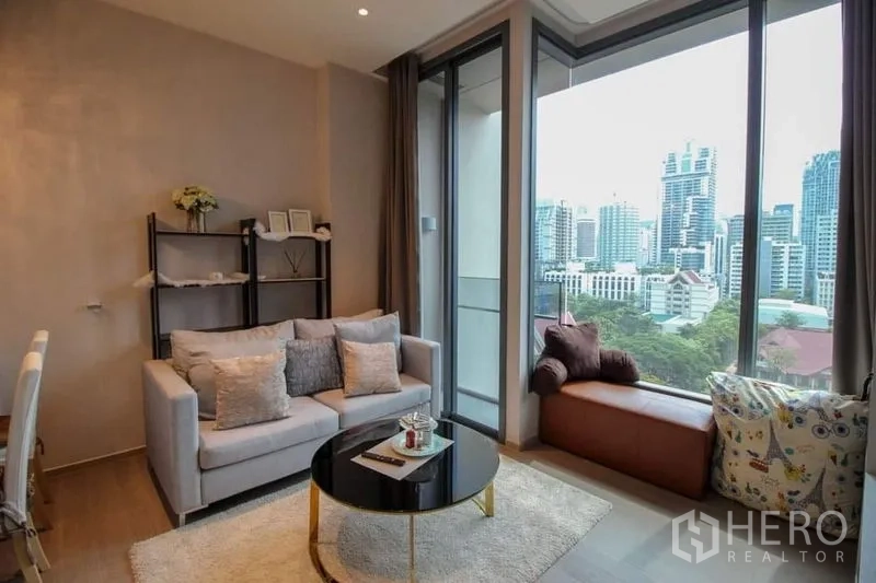 公寓 出售在Watthana, Bangkok - 客厅带窗边座与落地玻璃通往阳台，框景城市风光。
