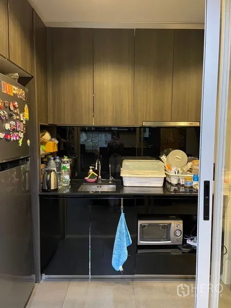 办公空间 出租在Phaya Thai, Bangkok - 紧凑茶水间，深色橱柜、水槽、冰箱与微波炉。