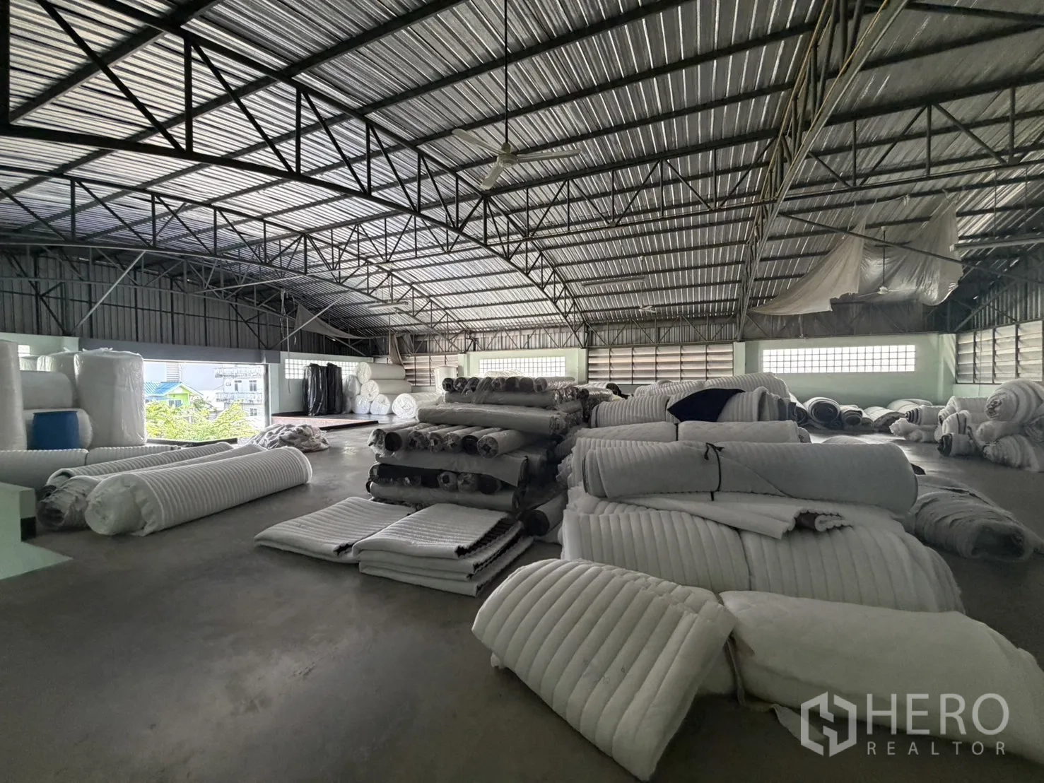 工厂 for rent or sale in Bang Bon, Bangkok - 顶层仓库，拱形金属屋顶，堆满布卷。