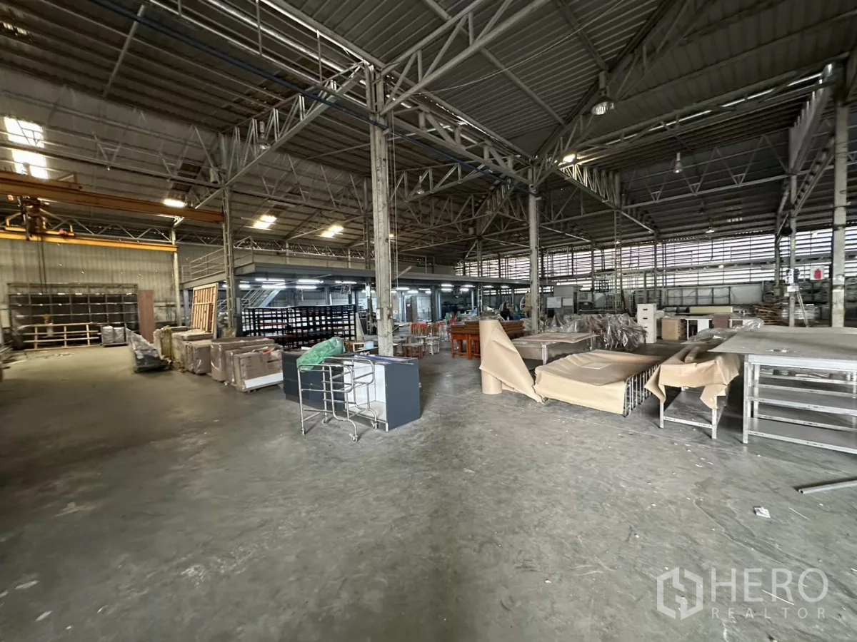 Warehouse for rent in Yan Nawa, Bangkok - Spacious factory-style floor with materials staged and mezzanine platforms on both sides.