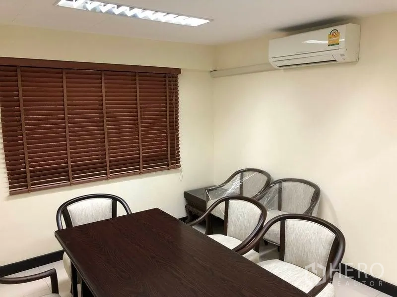 Home Office for rent in Khlong Toei, Bangkok - Meeting room featuring wooden table, chairs, window blinds and wall-mounted air conditioner.