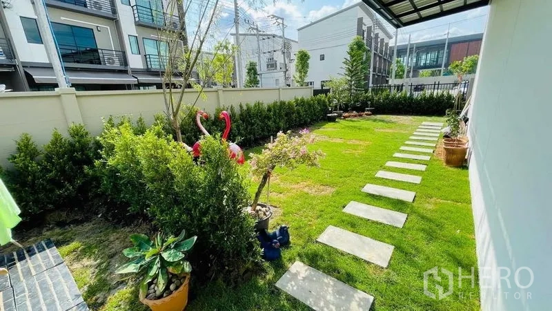 联排别墅 出租或出售在Prawet, Bangkok - 私家庭院侧院宽阔，草坪、踏步石与盆栽绿植。