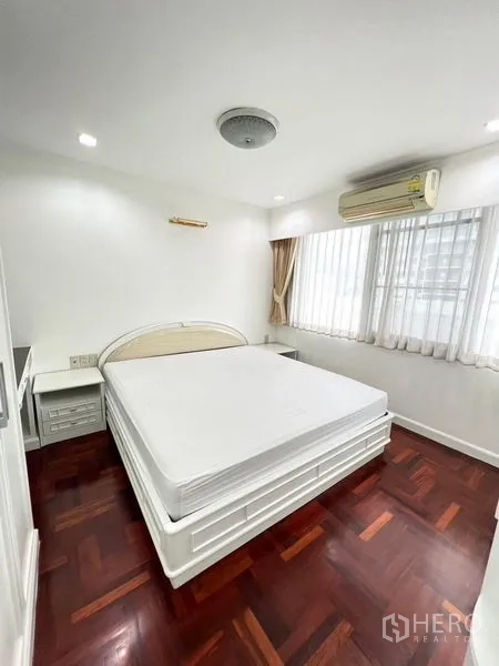 公寓 出租在Watthana, Bangkok - 角落卧室，大片窗户、双人床、空调及深色木地板。