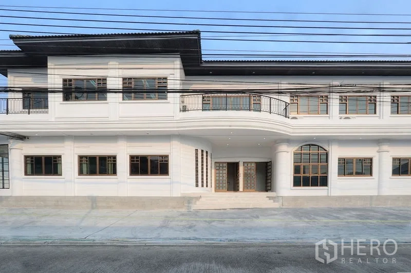 办公空间 出租在Bang Na, Bangkok - 双层办公楼立面，带阳台与格栅窗，宽阔街道旁的有顶入口。