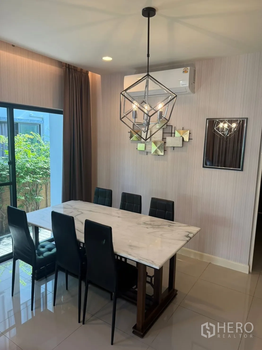 Detached House for rent in Prawet, Bangkok - Close-up of the dining area showing a modern chandelier and window to greenery.