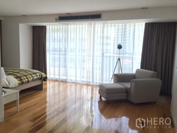 คอนโด ให้เช่าในWatthana, Bangkok - ห้องนอนหลักกว้างขวาง มีผ้าม่านโปร่งจรดพื้น พื้นไม้ และเก้าอี้เอนพร้อมสตูล