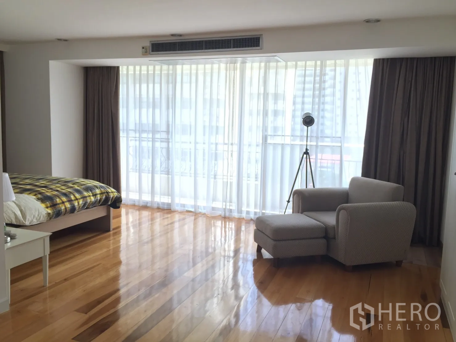 คอนโด ให้เช่าในWatthana, Bangkok - ห้องนอนหลักกว้างขวาง มีผ้าม่านโปร่งจรดพื้น พื้นไม้ และเก้าอี้เอนพร้อมสตูล