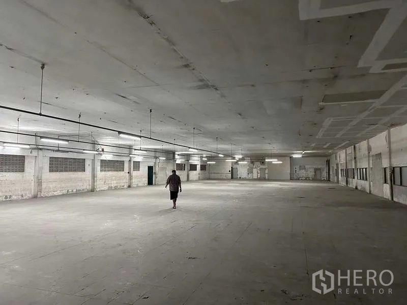 Factory for rent or sale in Bang Phli, Samut Prakan - Expansive production hall with suspended lights and concrete flooring.