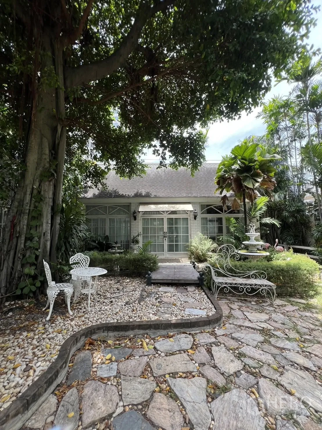 Detached House for rent in Phra Khanong, Bangkok - Front garden with a large tree, pebble paths and outdoor seating.