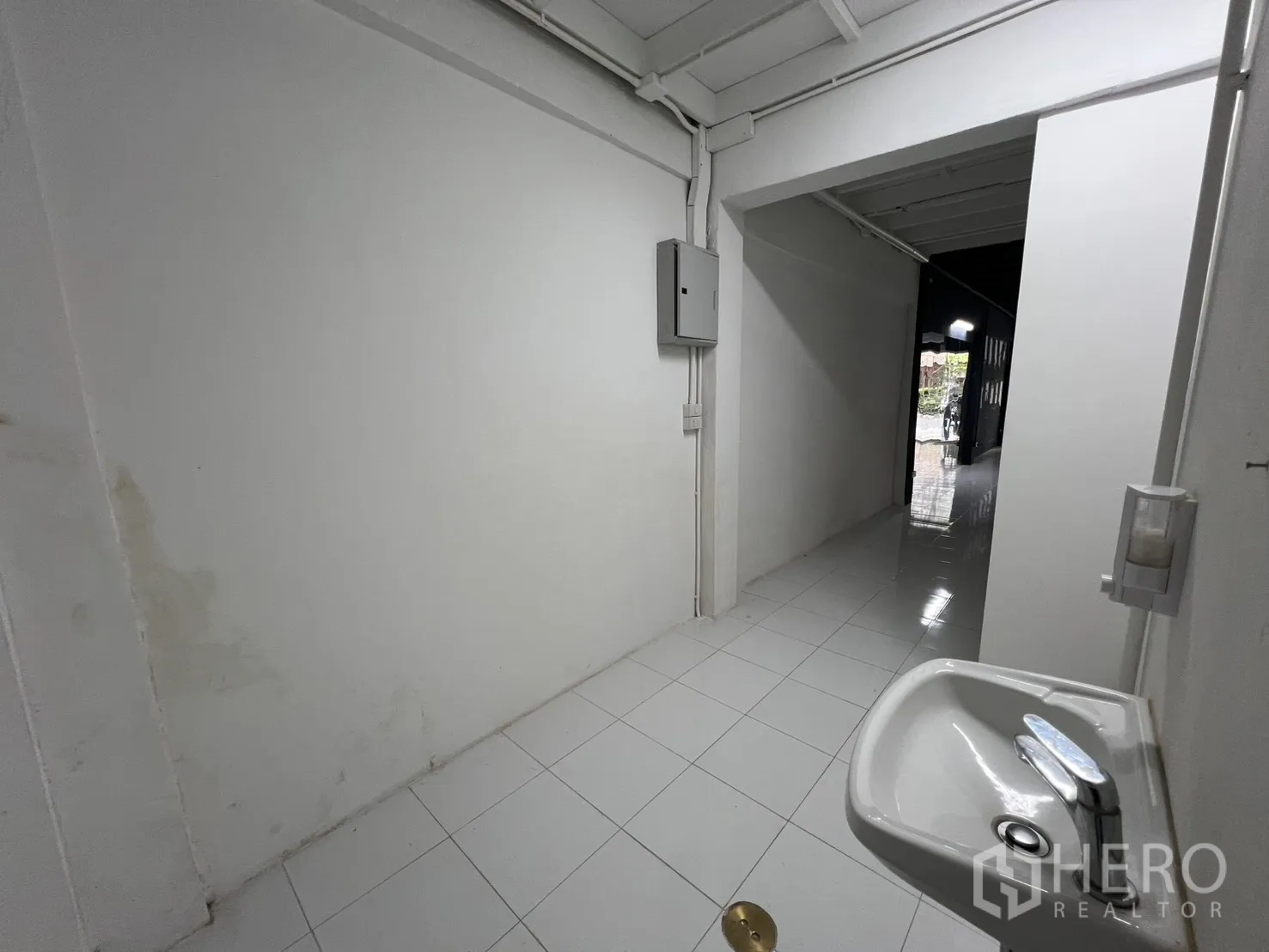 Shophouse for rent or sale in Khlong Toei, Bangkok - Hallway with wall-mounted sink leading toward the shopfront.
