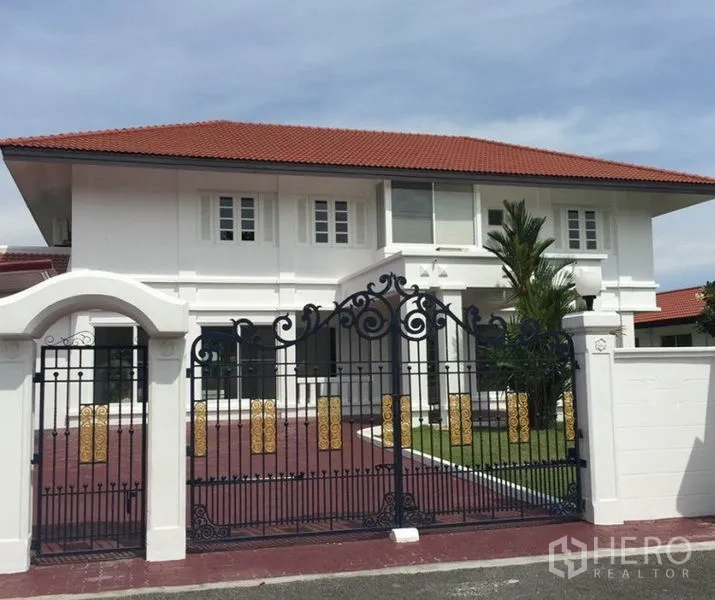 Detached House for rent in Bang Phli, Samut Prakan - Two-storey white detached house with red tile roof and ornate wrought-iron gate.