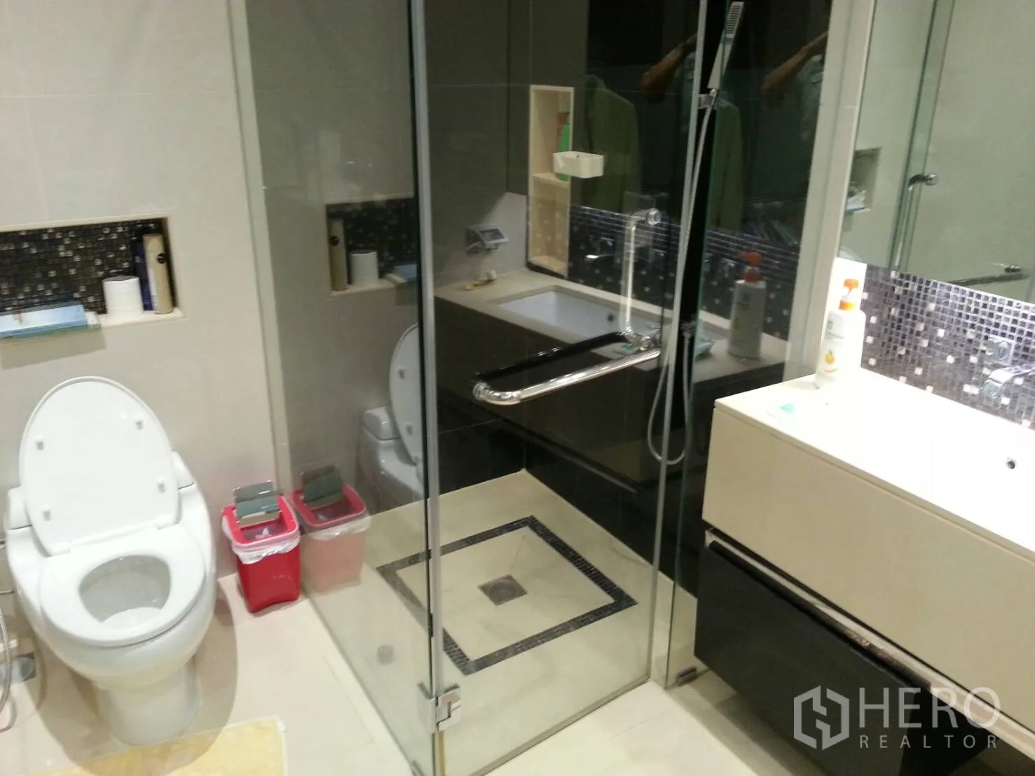 Condominium for rent or sale in Khlong Toei, Bangkok - Contemporary bathroom with glass-enclosed shower, bathtub, vanity and mosaic tile accents.