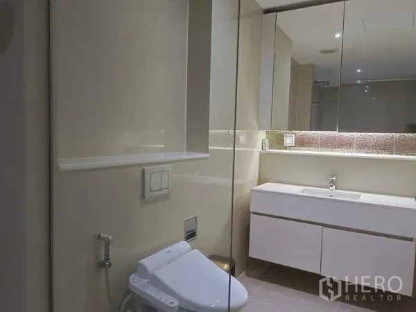 Condominium for rent in Watthana, Bangkok - Modern bathroom featuring a long floating vanity, large mirror and smart toilet.
