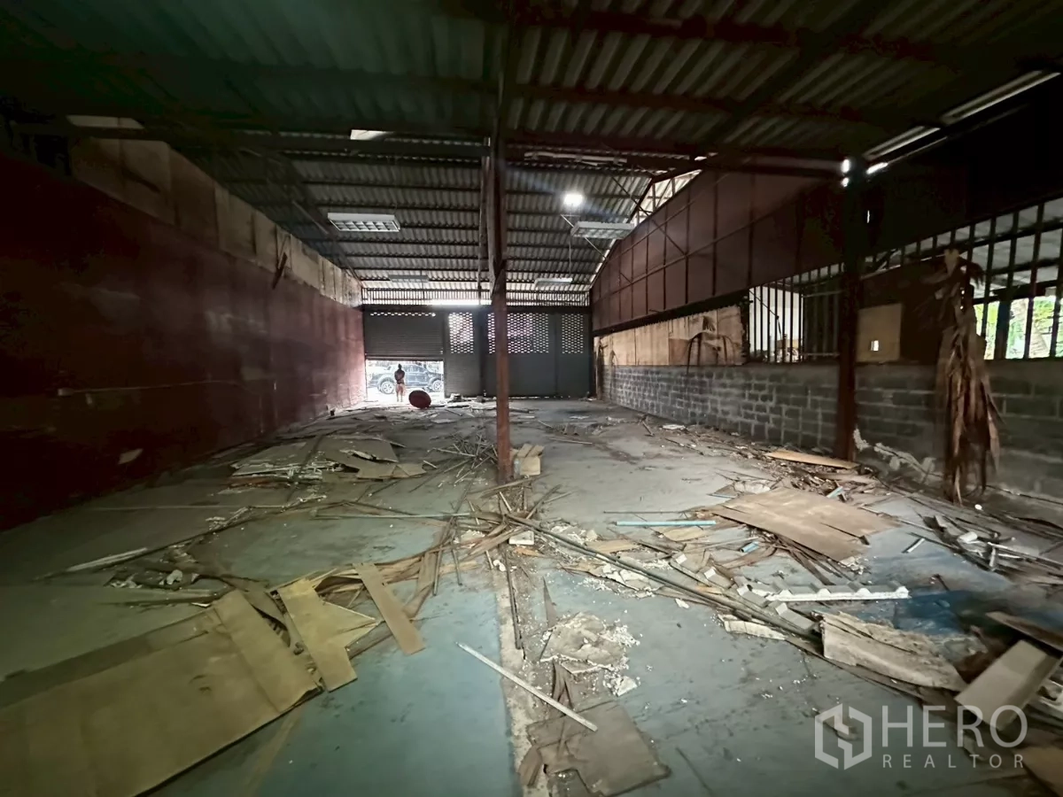 Warehouse for rent or sale in Yan Nawa, Bangkok - Narrow warehouse aisle with metal walls, overhead lights and a rear roller door.