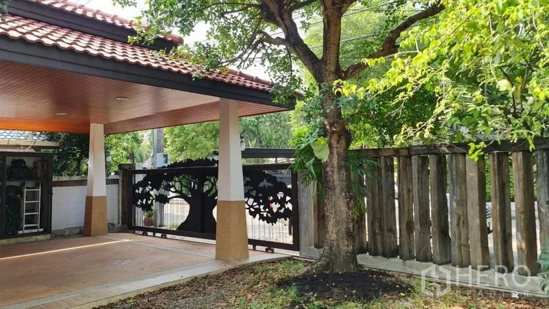 Detached House for rent in Saphan Sung, Bangkok - Front carport beside a mature tree and rustic wooden fence.