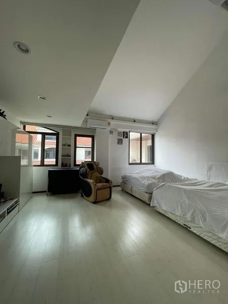 Townhouse for sale - Spacious bedroom with twin beds, massage chair and multiple windows.