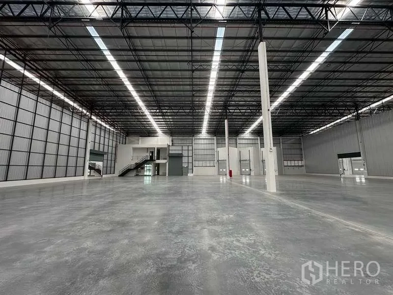 Warehouse for rent in Bang Phli, Samut Prakan - Wide-angle view of open warehouse space with steel trusses and support columns.