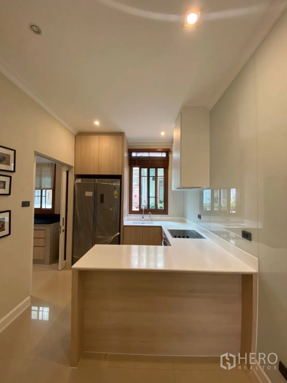 Detached House for rent in Bang Phli, Samut Prakan - Kitchen overview with breakfast bar, tall refrigerator and window bringing natural light.