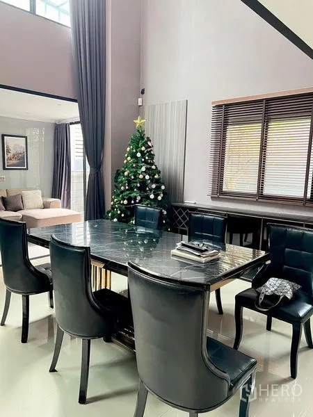Townhouse for rent in Saphan Sung, Bangkok - Dining area with high ceiling, marble-top table and tall curtains.
