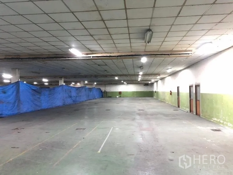 工厂 出租在Lat Krabang, Bangkok - 开阔厂房空间，蓝色防水布分隔，地漏与侧门齐全。