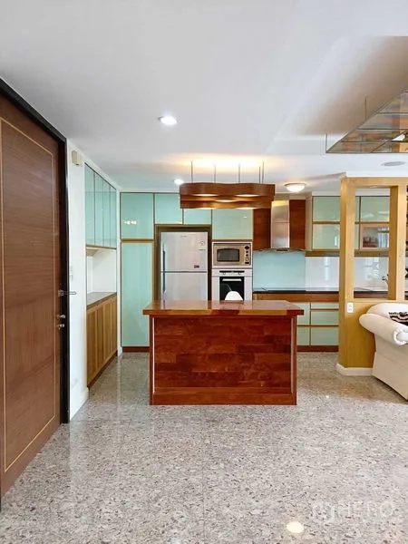 公寓 出租在Watthana, Bangkok - 开放式厨房设木质中岛，薄荷绿柜体，旁接客厅与天花灯光。