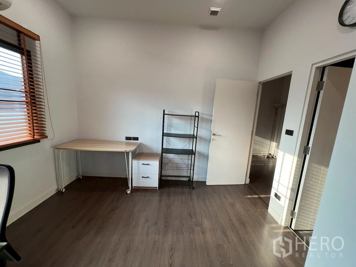 Detached House for rent in Bang Kapi, Bangkok - Corner view of study room with rolling table and metal shelving on wood flooring.