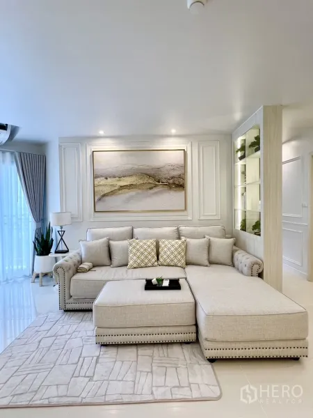 Condominium for rent in Yan Nawa, Bangkok - Bright sitting area with L-shaped sofa, artwork, and balcony doors with curtains.