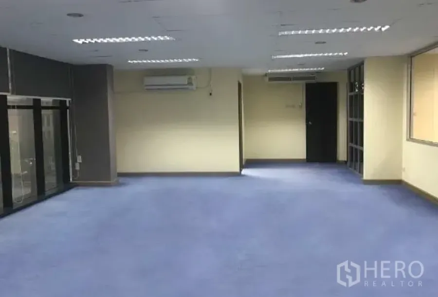 Office Space for rent in Bang Rak, Bangkok - Spacious open office with blue carpet, ceiling lights and air conditioning.
