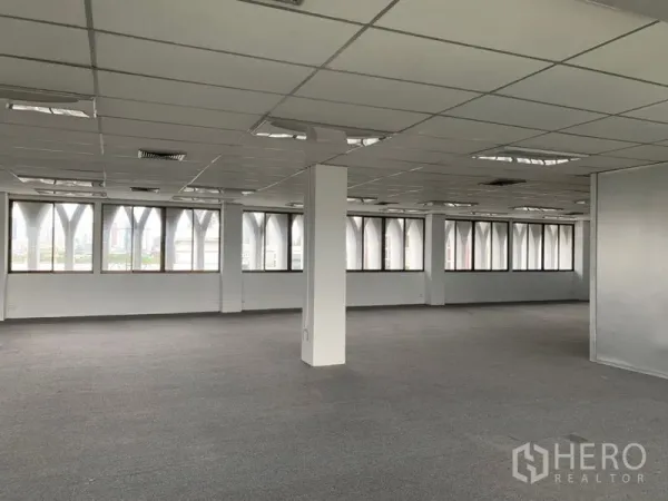 Office Space for rent in Ratchathewi, Bangkok - Corner office area with wide windows and arched exterior frames, featuring suspended ceiling lighting.