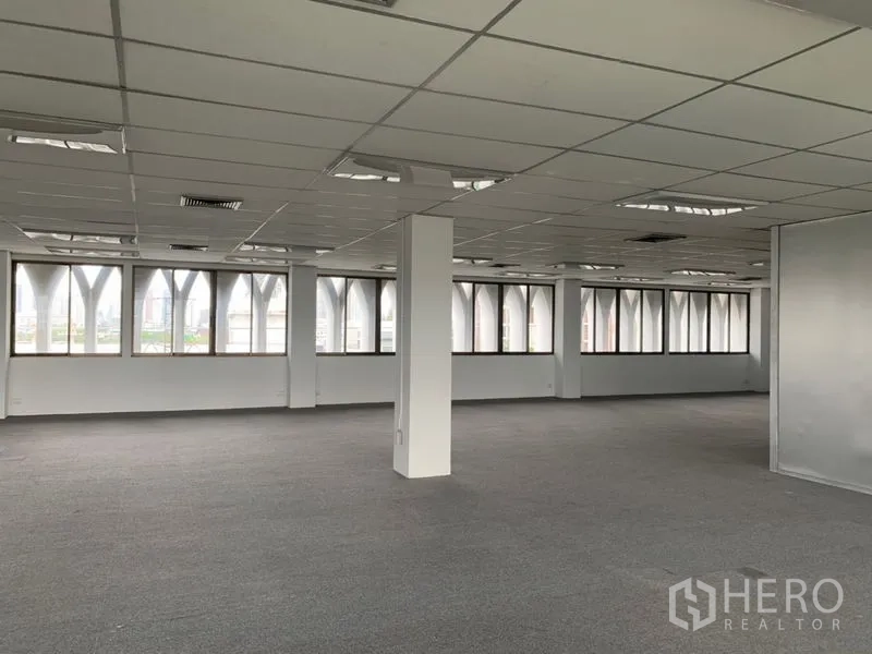 Office Space for rent in Ratchathewi, Bangkok - Corner office area with wide windows and arched exterior frames, featuring suspended ceiling lighting.