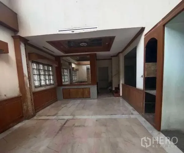 独立式住宅 出售在Phra Khanong, Bangkok - 客厅空间开阔，挑高天花、仿大理石地面与木质墙面，适合翻新设计。