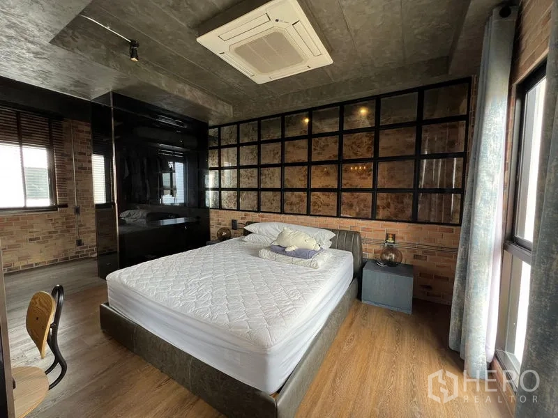 Townhouse for rent in Saphan Sung, Bangkok - Industrial-style bedroom with brick feature wall, grid shelving headboard, and king bed.