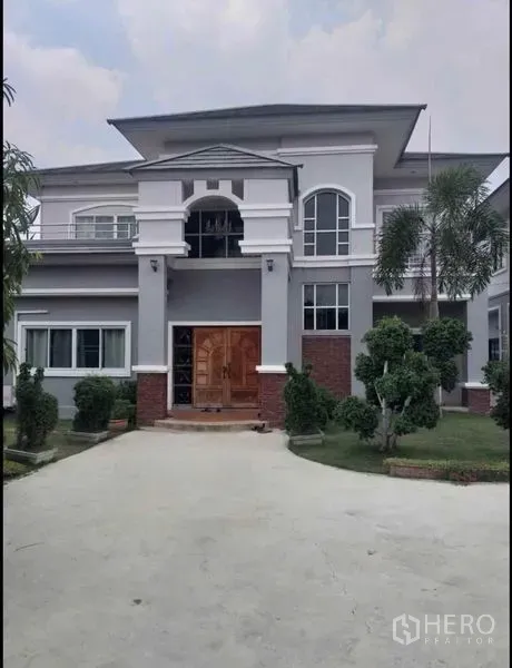 Detached House for sale in Lam Luk Ka, Pathum Thani - Front façade of the main two-storey house with arched windows and a wooden door.