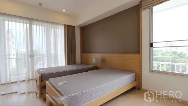 公寓 出租在Watthana, Bangkok - 明亮卧室配双床，落地窗连通阳台景观。