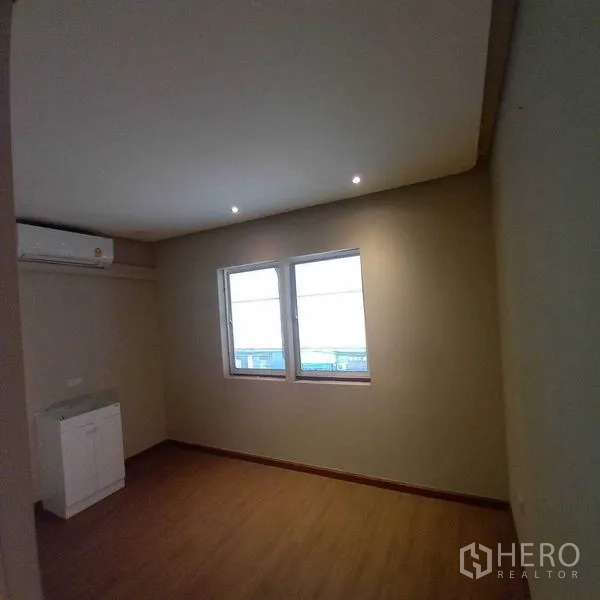 Shophouse for rent in Watthana, Bangkok - Upper-floor room with twin windows, recessed lights and a small sink cabinet
