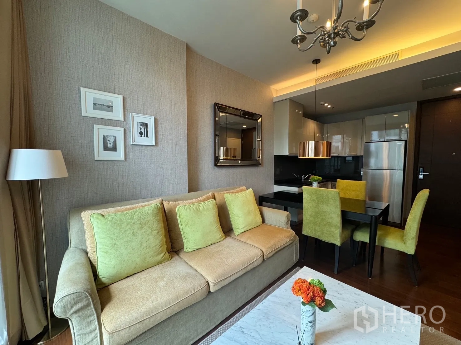 คอนโด ให้เช่าในWatthana, Bangkok - ห้องนั่งเล่นสไตล์โมเดิร์น โซฟาสีเบจ หมอนสีเขียว โคมแชนเดอเลียร์ เชื่อมต่อพื้นที่ทานอาหารและครัว