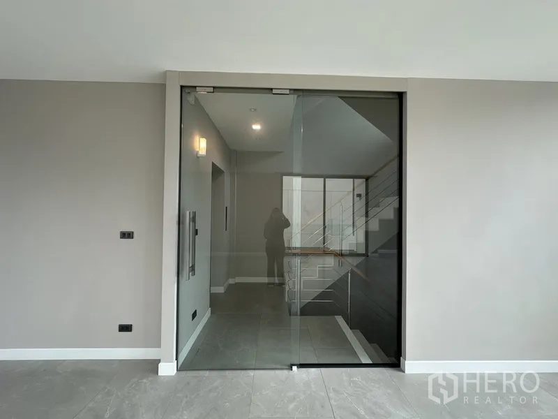家庭办公室 for rent or sale in Suan Luang, Bangkok - 无框玻璃门通往走廊与楼梯。