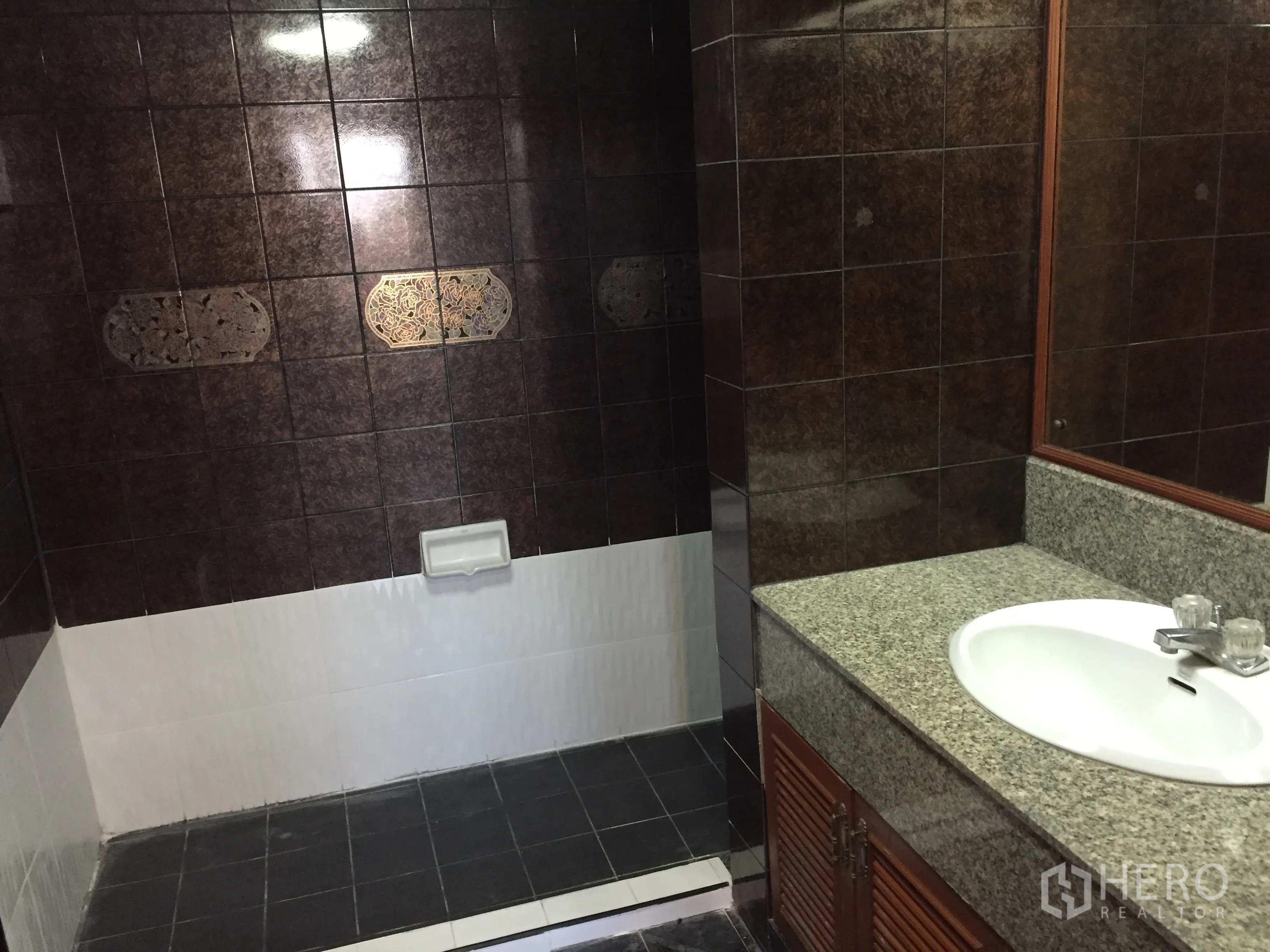 Condominium for rent in Watthana, Bangkok - Bathroom with dark tiled walls, step-in shower area, granite countertop vanity and large mirror.