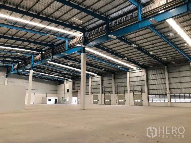 Warehouse for rent in Bang Phli, Samut Prakan - Warehouse interior with roller shutter access and a mezzanine office block.