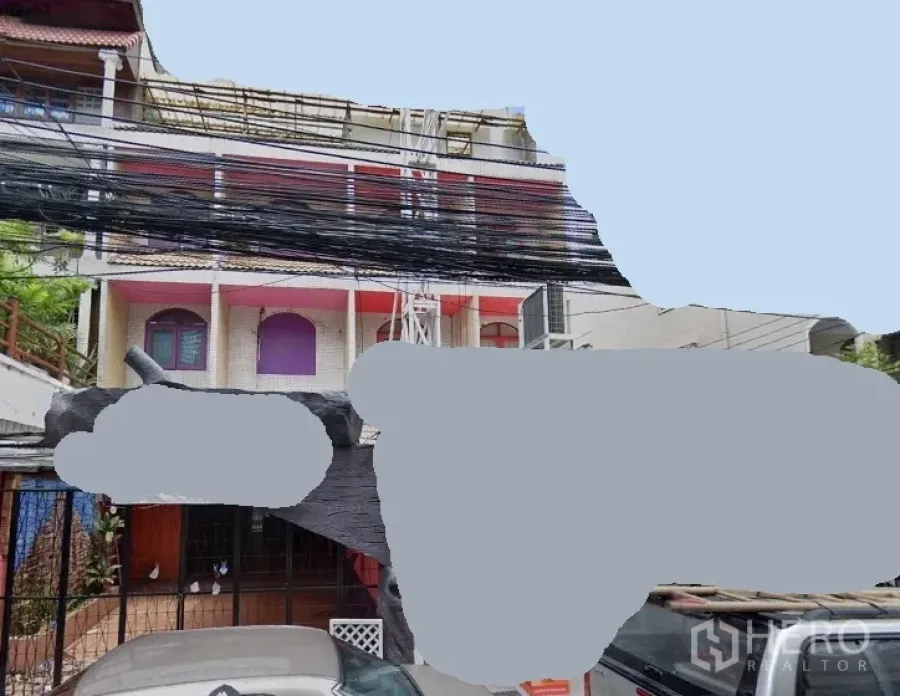 Townhouse for rent in Watthana, Bangkok - Three-storey townhouse exterior with pink balconies, arched windows, gated entry and urban power lines in the Sukhumvit–Asok area of Bangkok.