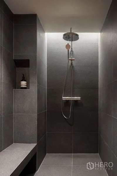 Condominium for rent in Phaya Thai, Bangkok - Walk-in shower with rain showerhead, built-in bench and dark stone tiles.