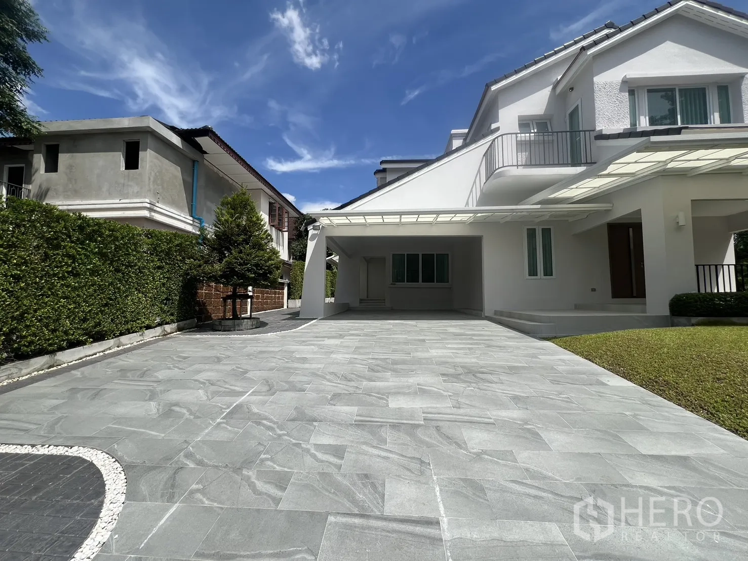 Detached House for rent in Mueang Samut Prakan, Samut Prakan - Spacious driveway leading to a carport and balcony, with hedges along the boundary.