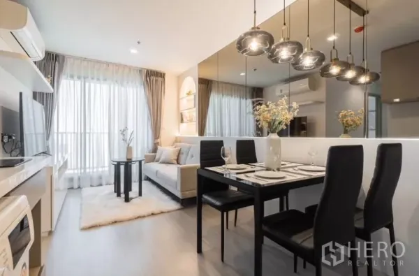 公寓 出租在Chatuchak, Bangkok - Life Ladprao 两卧公寓明亮客餐厅，吊灯、镜面墙与飘窗帘。