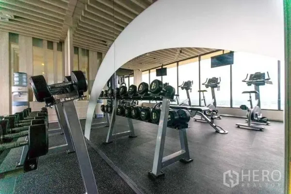 Condominium for rent in Khlong Toei, Bangkok - Modern fitness center with free weights and cardio machines facing city views.