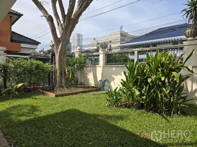 独立式住宅 出租在Watthana, Bangkok - 前花园有成树、灌木和高围栏，位于瓦塔纳城区。