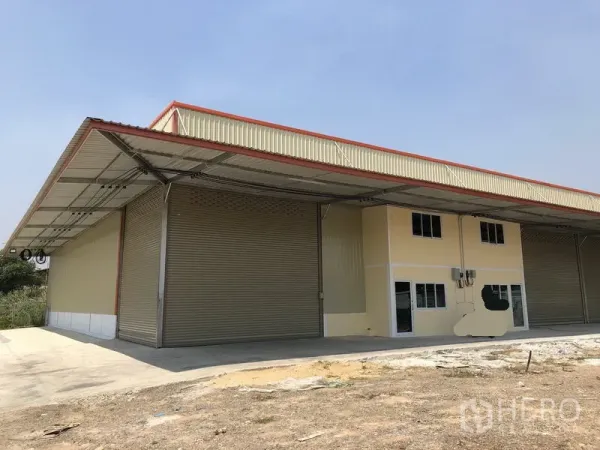 Factory for rent in Khlong Luang, Pathum Thani - Front exterior of a modern warehouse with covered loading bay, roller shutters and a two-storey office block.