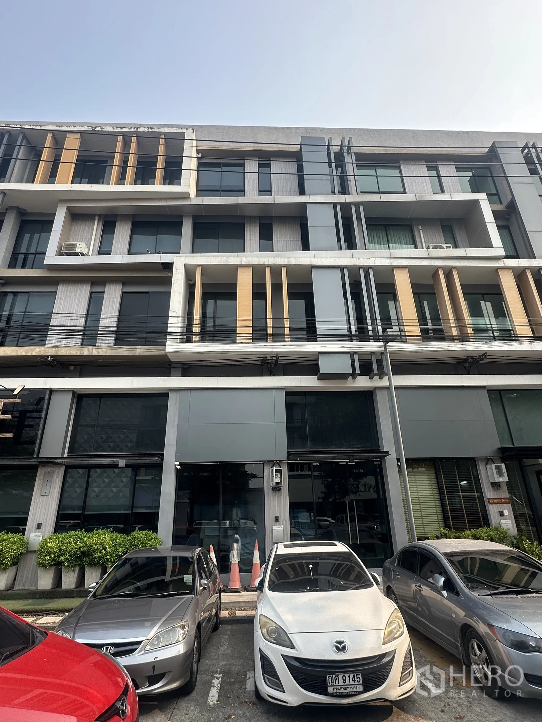 Home Office for rent in Bang Khen, Bangkok - Modern four-storey home office building with glass facade, vertical accents, and front parking spaces.