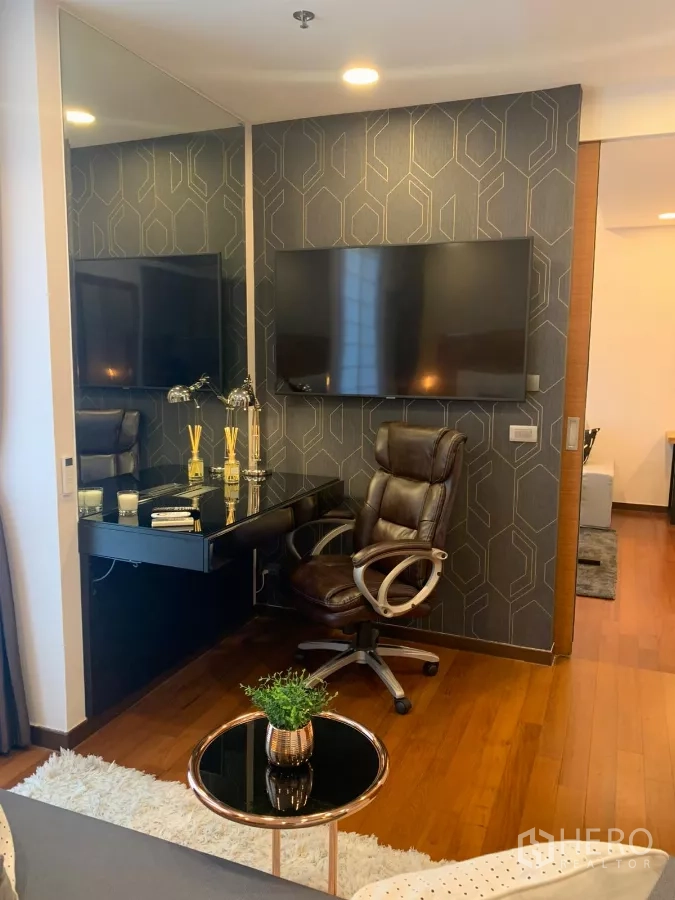 Condominium for sale in Khlong Toei, Bangkok - Bedroom corner with glossy work desk, leather chair and wall‑mounted TV.